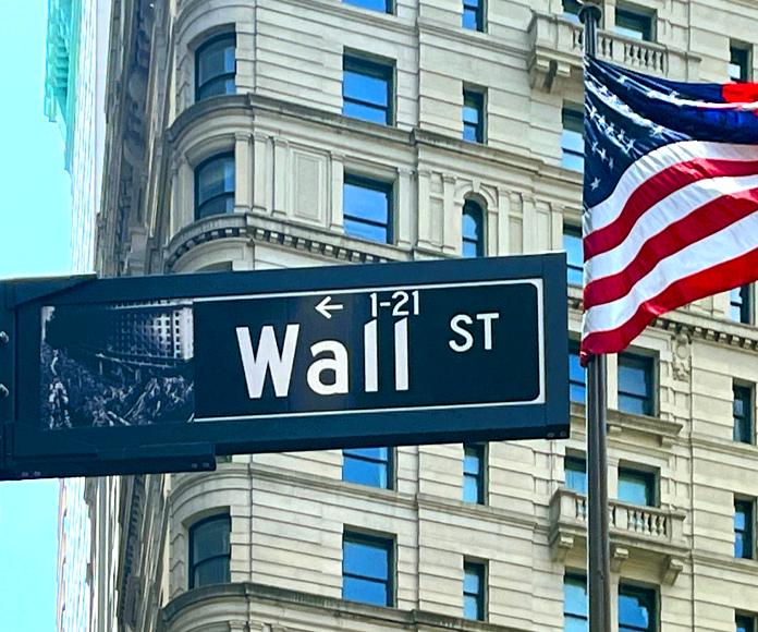 Señal de Wall Street junto a bandera de los EE. UU.