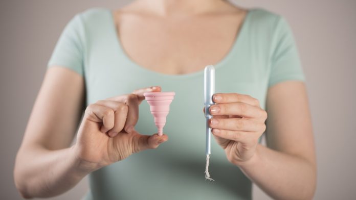 Mujer sosteniendo una copa menstrual y un tampón