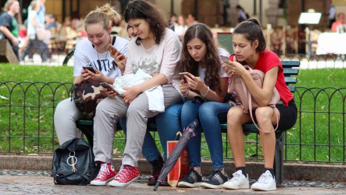 Chicas sentadas viendo sus móviles