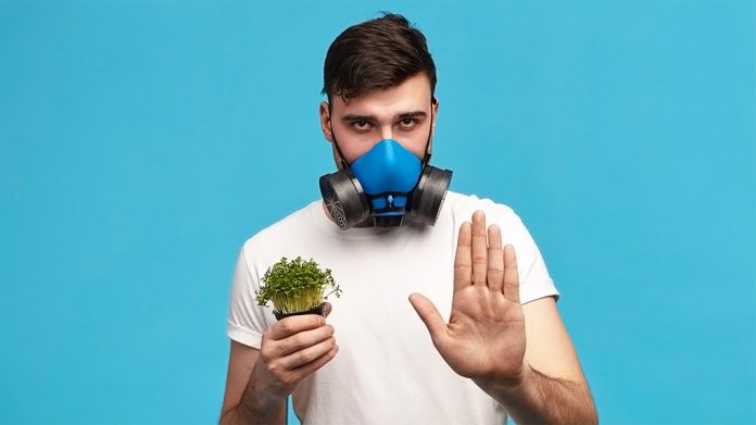 hombre con máscara de gas sujetando una planta