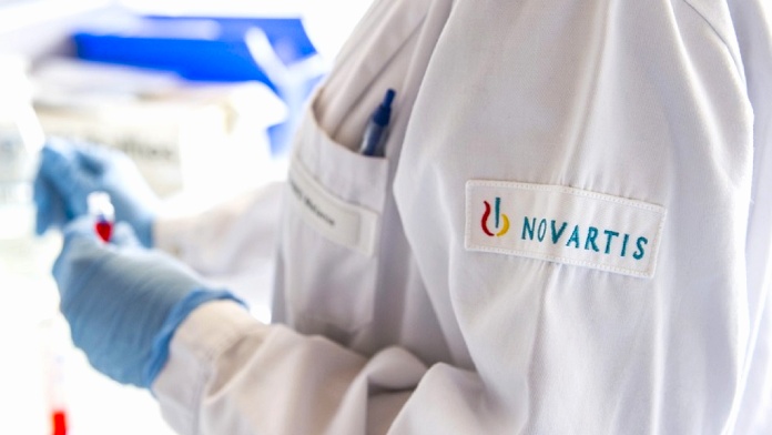 Investigador en laboratorio con bata con el logo de Novartis