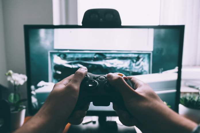 persona jugando videojuegos frente a una pantalla, sosteniendo el control.